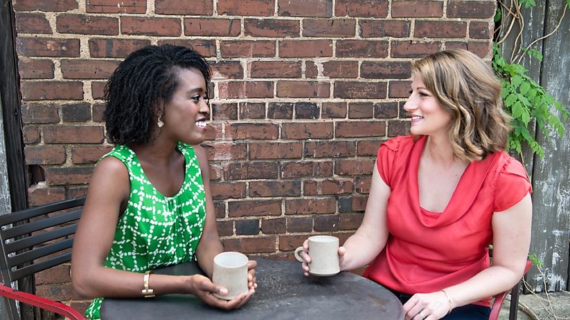 Lydia Scarlett and Cara Stevens talking over coffee at an outdoor table